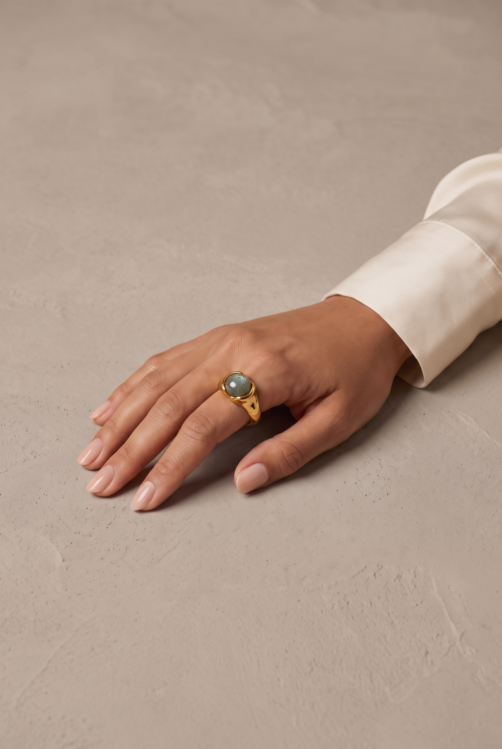 Hammered grey stone ring in gold worn on the hand